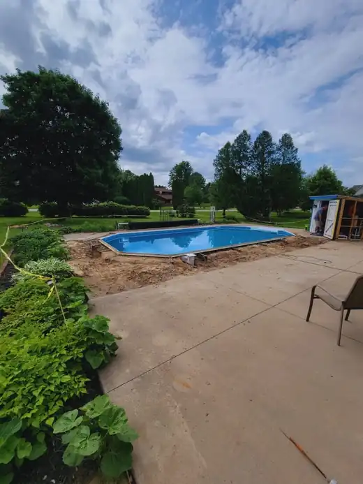 An in-progress in-ground pool beside a patio, the pit still open