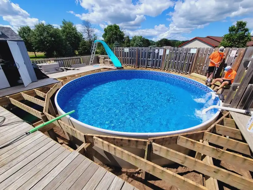 A round pool being built into a wooden deck frame, crew working at the far side