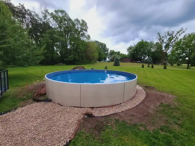 A freshly set round pool on a lawn with a gravel apron around the base