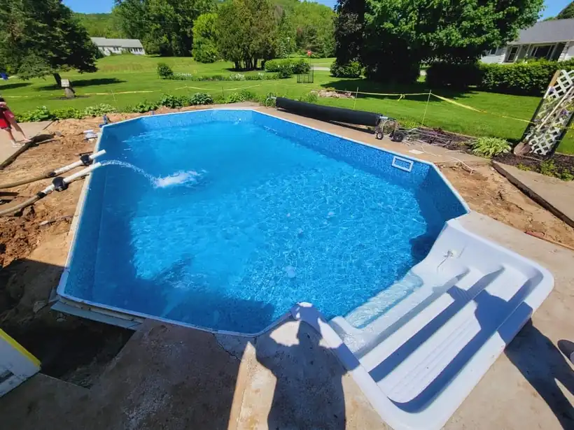An in-ground pool during installation with water filling over the new blue liner