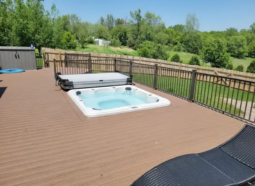 A square acrylic hot tub set flush in a composite deck, cover folded back, jets running